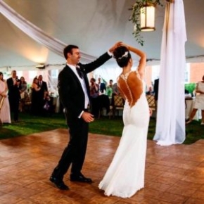 A happy couple dances at their wedding on a Teak style dance floor that complements their theme.