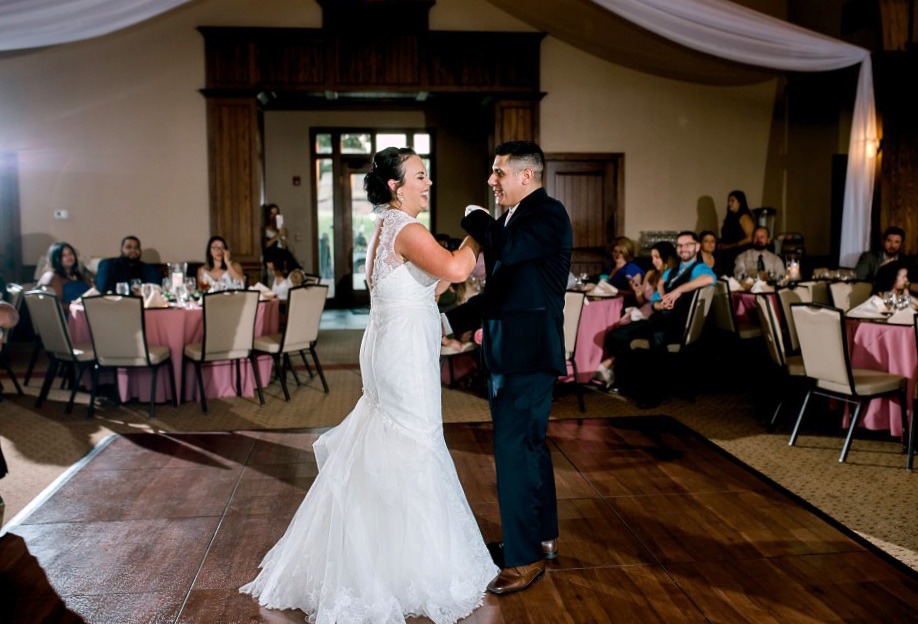 Happy couple dances on a Dark Maple Plus wedding dance floor