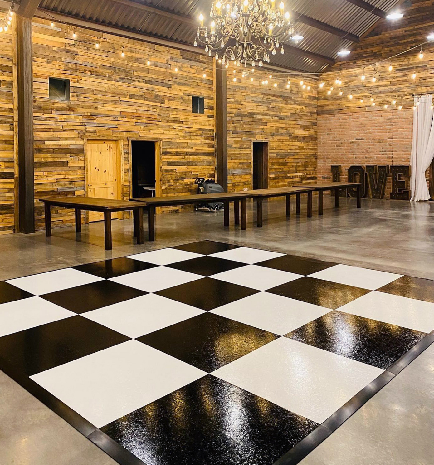 Slate black and white plus style dance floor in barn with chandelier