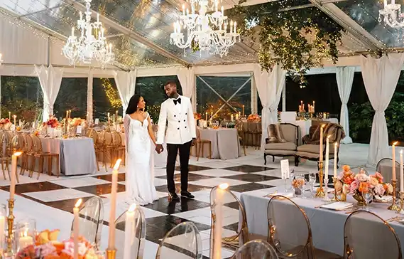 Couple on a black and white slate checkerboard dance floor in an event tent
