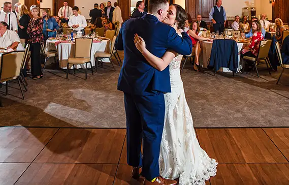 Bride and groom kiss on our dark maple dance floor.