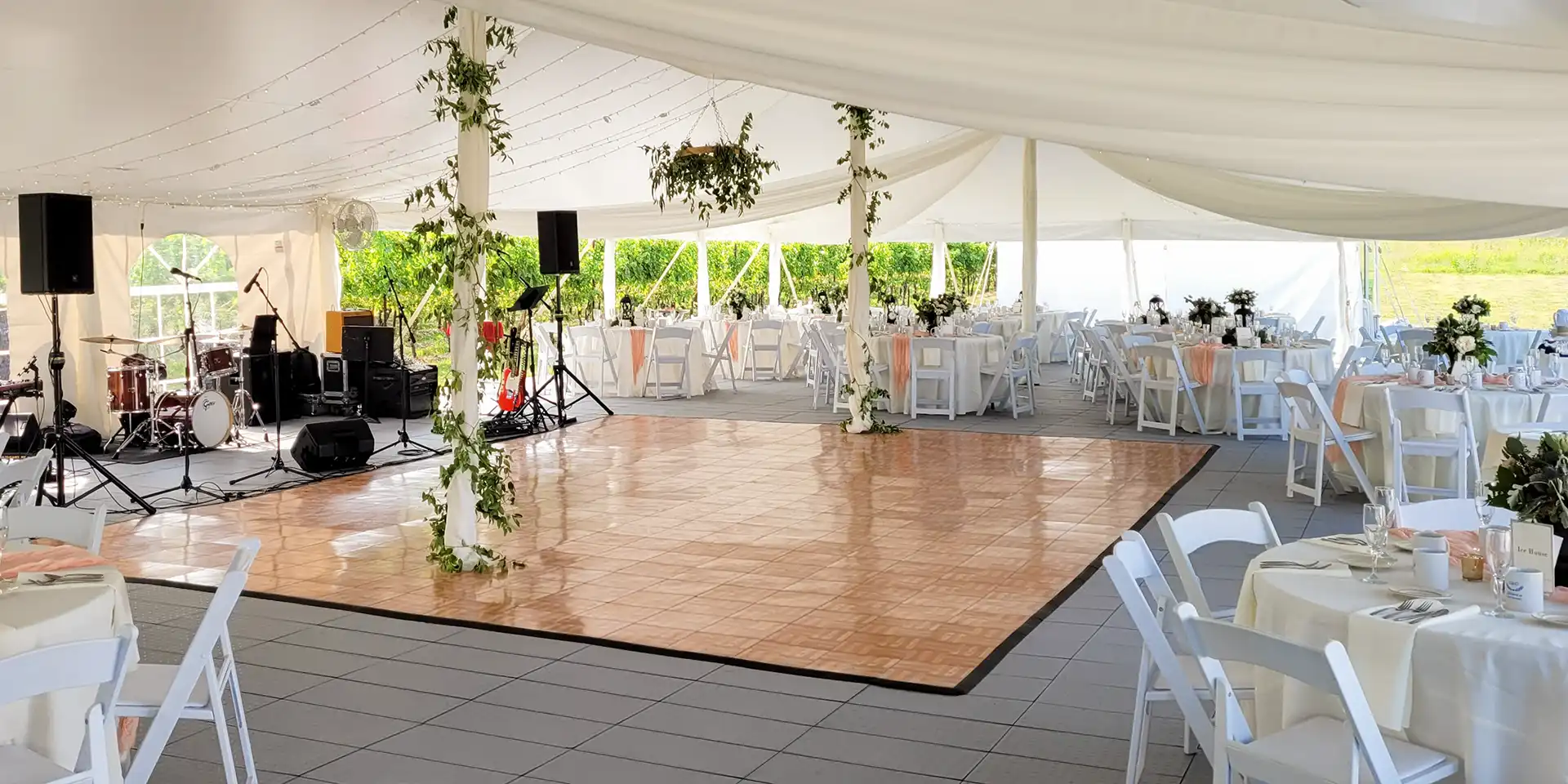 A dance floor in an event tent with FastDeck event flooring. A band is set up and there are tables and chairs for the guests.